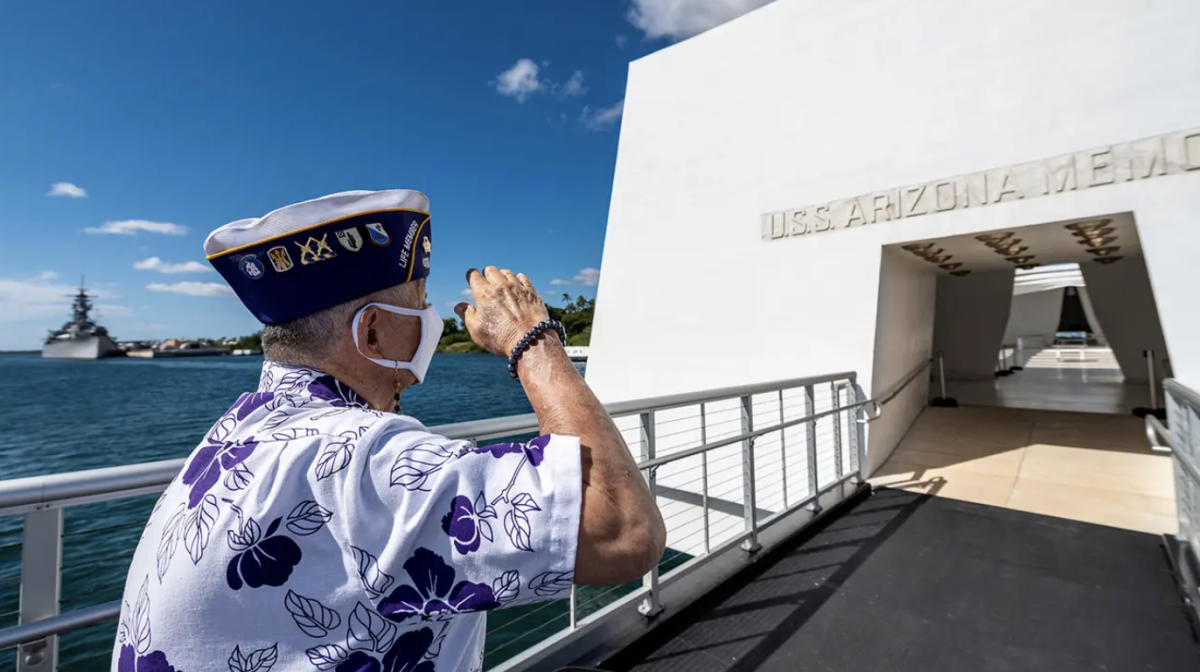 A veteran salutes the USS Arizona memorial in Hawaii.