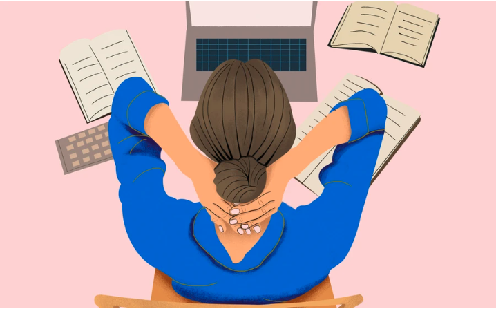 A woman works at her laptop and clasps both hands behind her head in a manner that indicates anxiety.