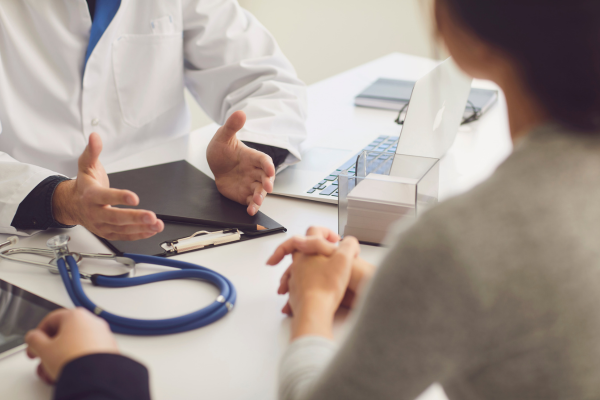 A doctor, face unseen, holds a discussion with a patient.