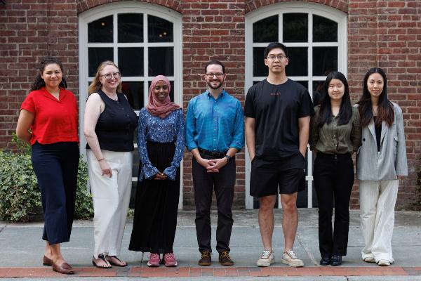 Group photo of PhD students standing on sidewalk