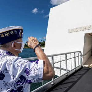 A veteran salutes the USS Arizona memorial in Hawaii.