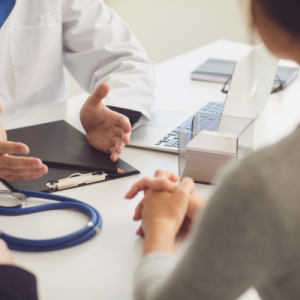A doctor, face unseen, holds a discussion with a patient.